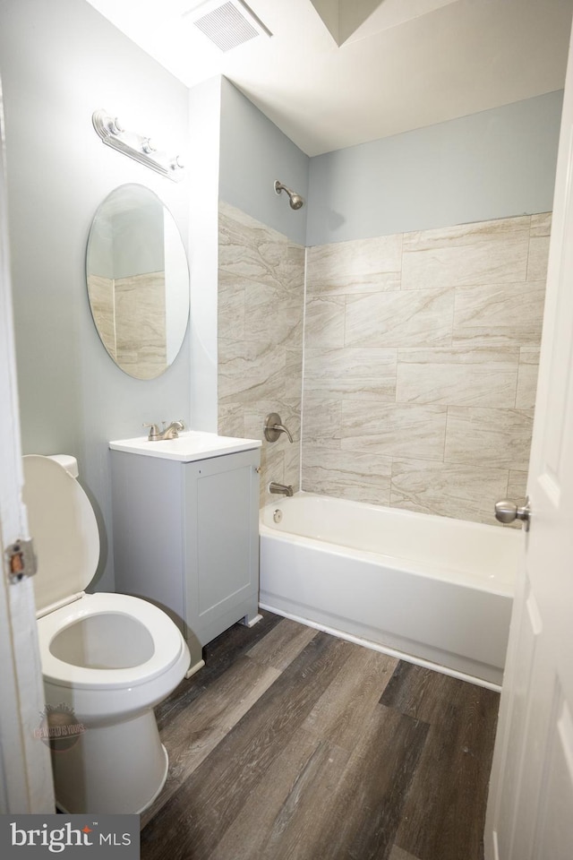 full bathroom with vanity, tiled shower / bath combo, wood-type flooring, and toilet