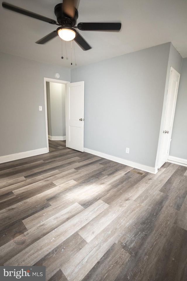 empty room with ceiling fan and dark hardwood / wood-style floors