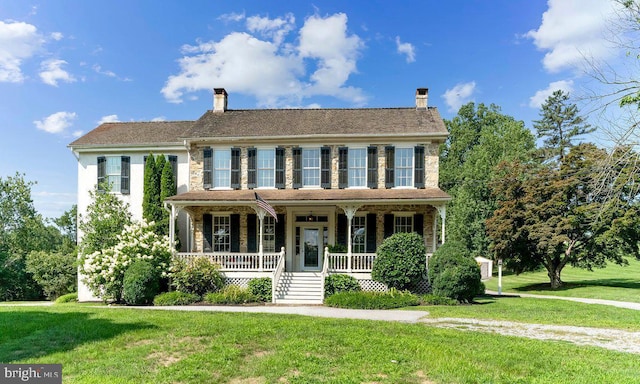 colonial inspired home featuring covered porch and a front lawn