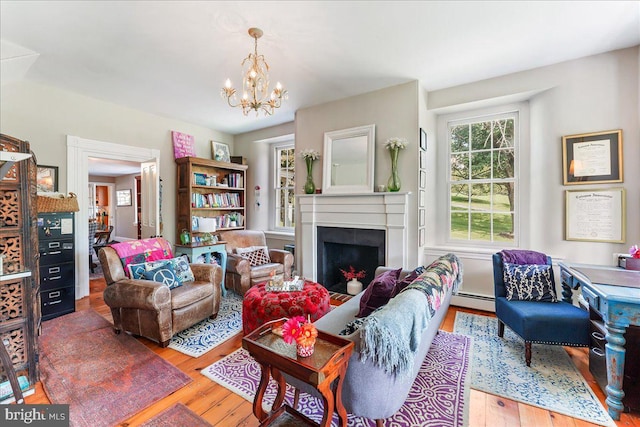 living room with hardwood / wood-style flooring, a baseboard heating unit, and a notable chandelier