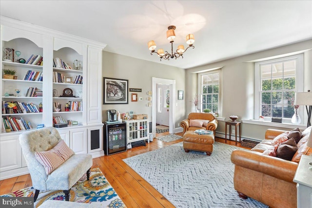 living area with an inviting chandelier, built in shelves, a baseboard radiator, and light wood-type flooring