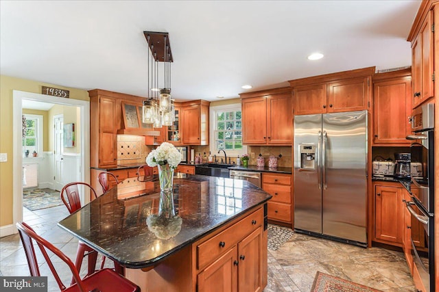 kitchen featuring a kitchen island, pendant lighting, a kitchen bar, dark stone counters, and stainless steel appliances