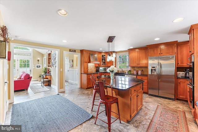 kitchen featuring pendant lighting, a wealth of natural light, a center island, and appliances with stainless steel finishes