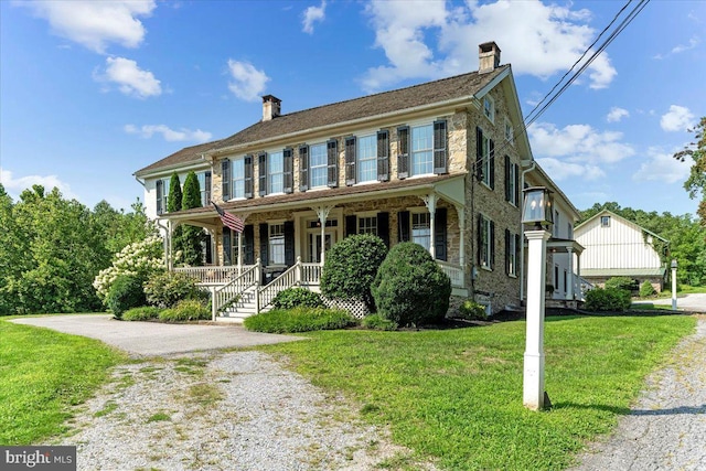 colonial inspired home with a front yard and covered porch