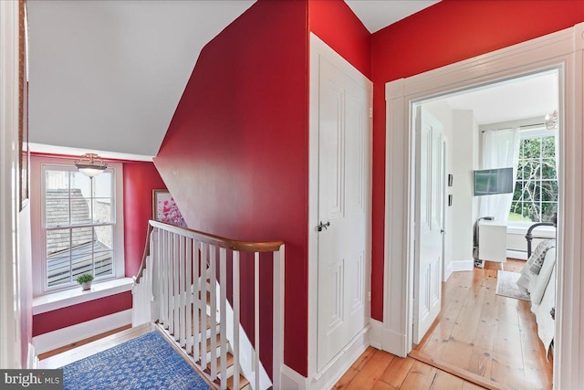 hall featuring lofted ceiling, a baseboard heating unit, and light wood-type flooring