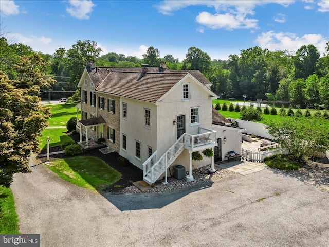 back of property featuring central AC unit and a lawn