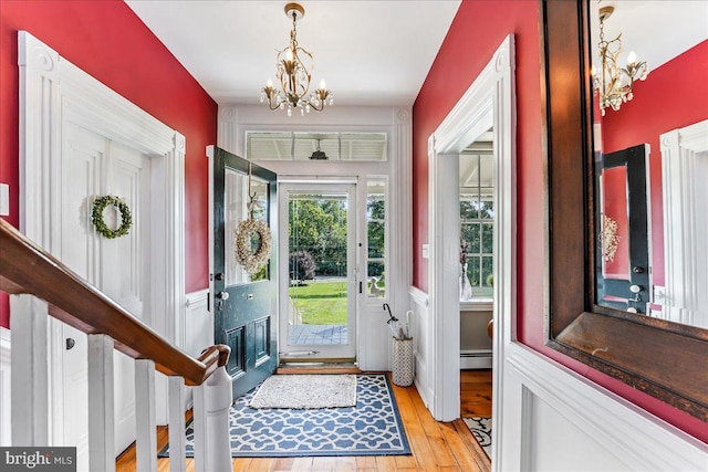 foyer entrance with a baseboard radiator, an inviting chandelier, and light wood-type flooring