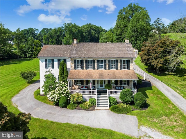 colonial inspired home with a front yard and covered porch