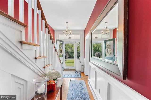 doorway to outside featuring a chandelier and light hardwood / wood-style flooring