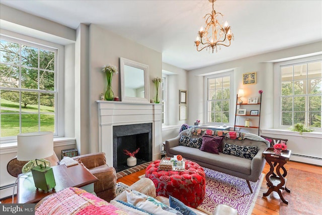 living room featuring hardwood / wood-style flooring, a baseboard radiator, and an inviting chandelier