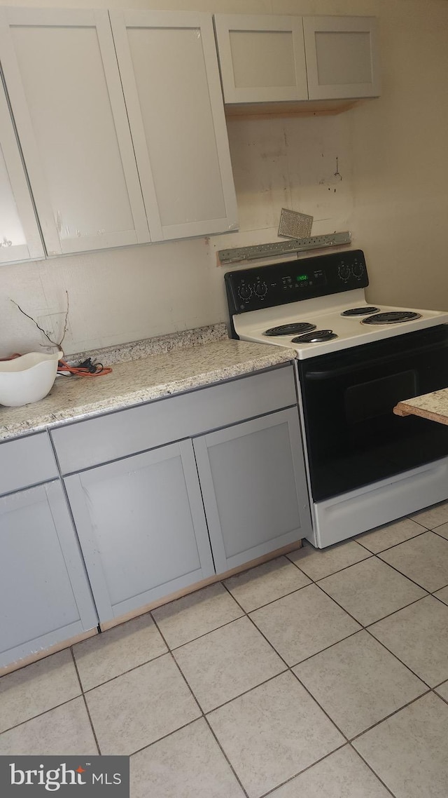 kitchen with light tile patterned floors, light countertops, electric range, and gray cabinetry