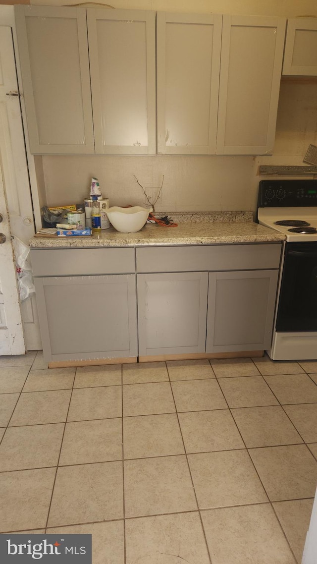 kitchen featuring white electric stove, light countertops, and light tile patterned floors