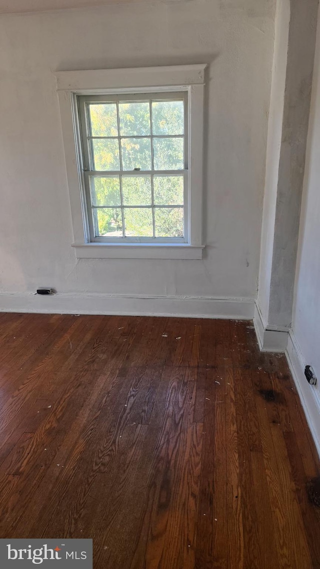 empty room with wood-type flooring and baseboards