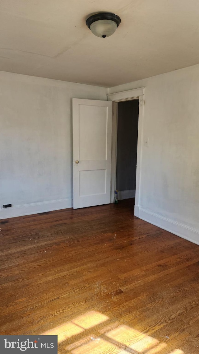 empty room with dark wood finished floors and baseboards