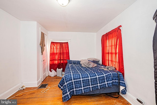 bedroom featuring baseboards, visible vents, and wood finished floors