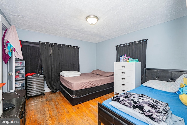 bedroom with a textured ceiling and wood finished floors