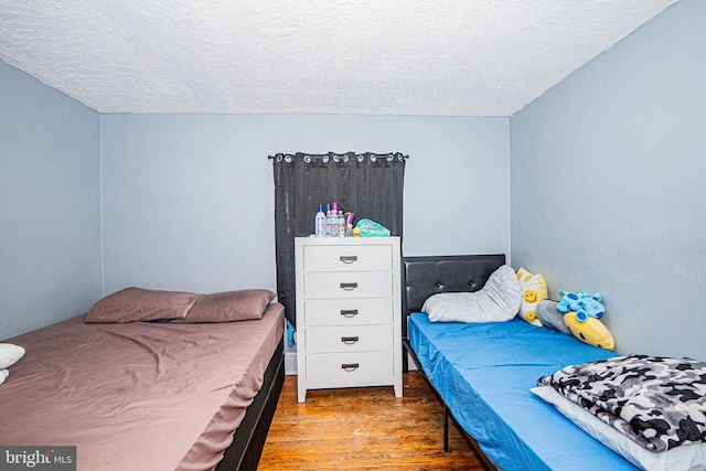 bedroom with a textured ceiling and wood finished floors