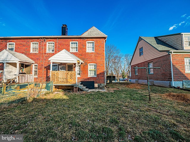 rear view of house with a shingled roof, brick siding, a lawn, and a chimney