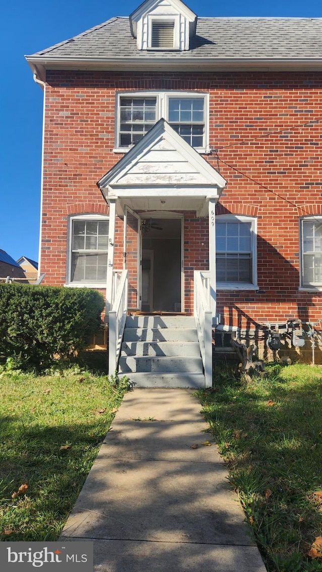 view of front of home featuring brick siding and a shingled roof