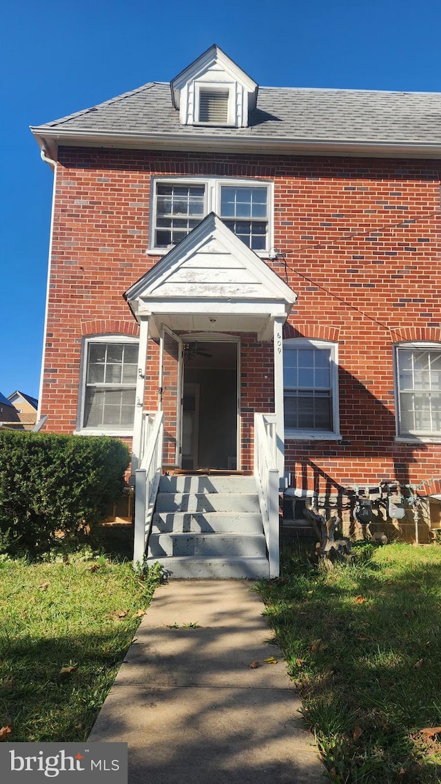 view of front facade featuring brick siding and roof with shingles