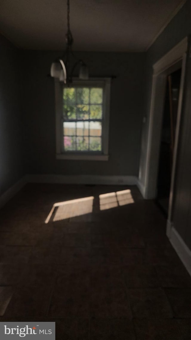 unfurnished dining area with baseboards and a notable chandelier