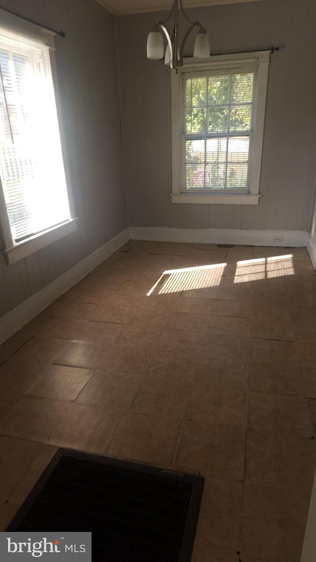 unfurnished room with tile patterned flooring, baseboards, and a notable chandelier