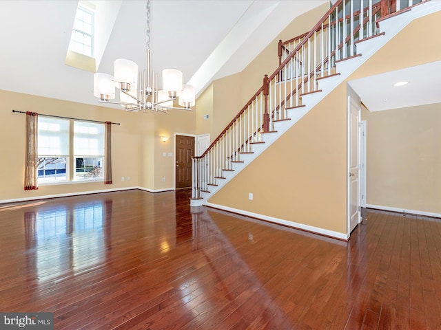 unfurnished living room featuring a high ceiling, hardwood / wood-style floors, and an inviting chandelier