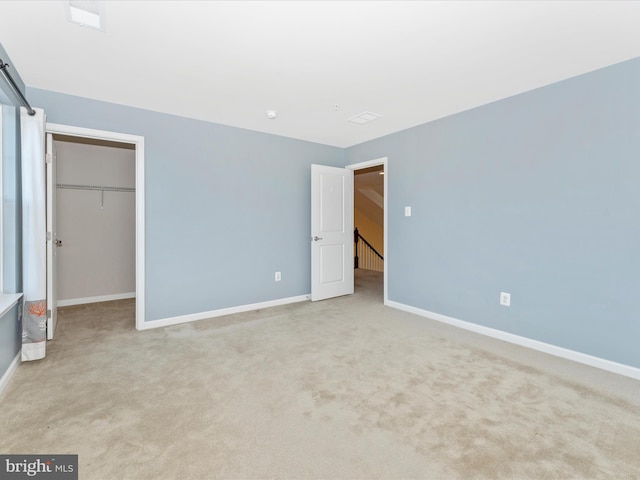 unfurnished bedroom with light carpet, a walk in closet, and a closet