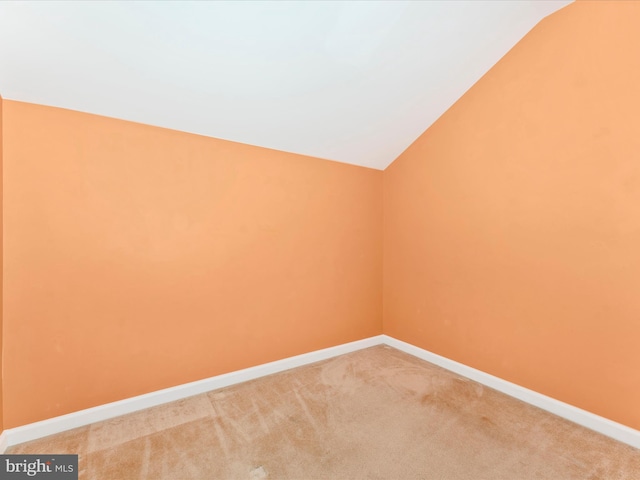 carpeted empty room with lofted ceiling