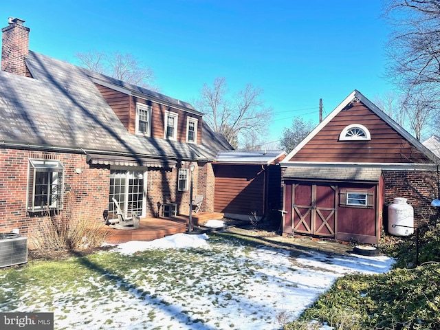 snow covered property with central AC unit and a deck