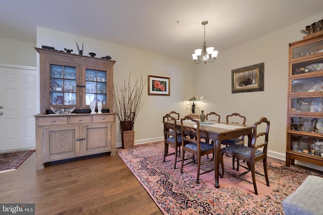 dining area with dark wood-type flooring and a notable chandelier