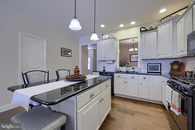 kitchen featuring white cabinets, a kitchen bar, and black appliances