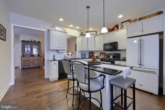 kitchen with dark hardwood / wood-style floors, decorative light fixtures, white cabinetry, a kitchen breakfast bar, and black appliances