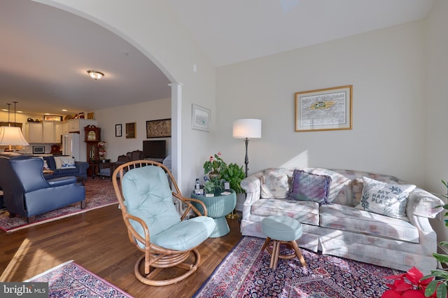 living room featuring decorative columns and dark hardwood / wood-style flooring