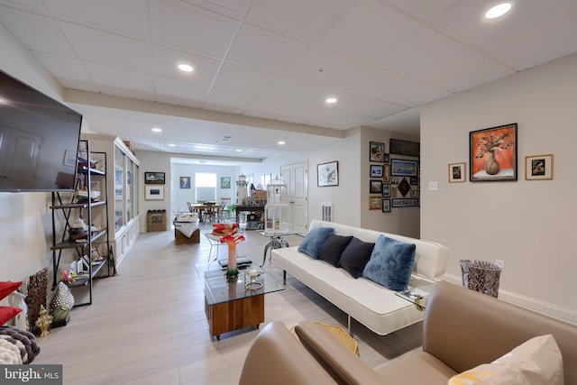 living room with a drop ceiling and light wood-type flooring