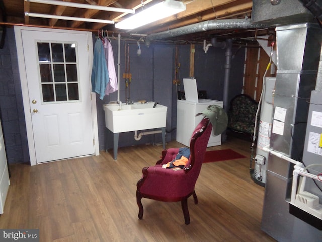 basement featuring water heater, washer and dryer, and hardwood / wood-style floors