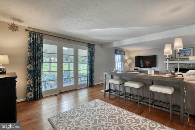 kitchen with dark hardwood / wood-style floors, a textured ceiling, a kitchen breakfast bar, and french doors