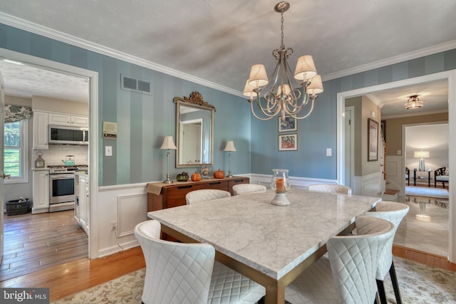 dining area featuring crown molding, a chandelier, and light wood-type flooring