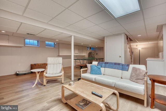 living room with a paneled ceiling and light hardwood / wood-style floors