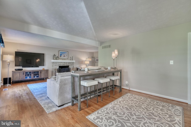 living room featuring a fireplace, light hardwood / wood-style flooring, and a textured ceiling