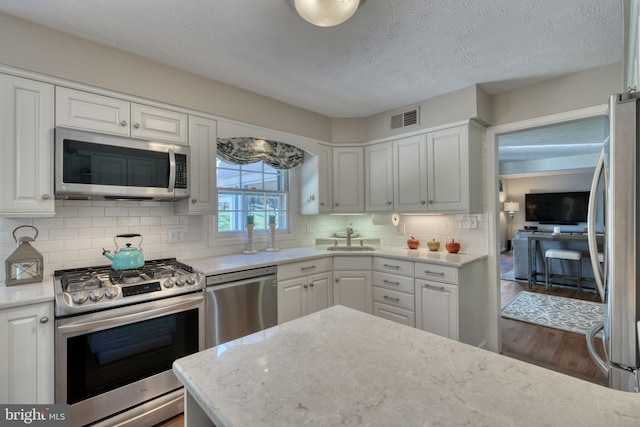 kitchen featuring stainless steel appliances, white cabinetry, tasteful backsplash, and dark wood-type flooring