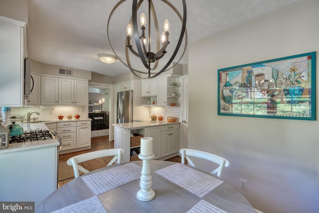 dining room featuring an inviting chandelier, dark hardwood / wood-style flooring, sink, and a textured ceiling