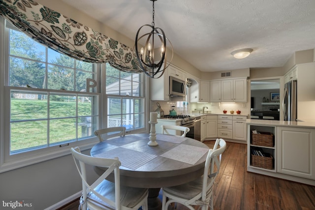 dining area with a notable chandelier, dark hardwood / wood-style floors, and a textured ceiling