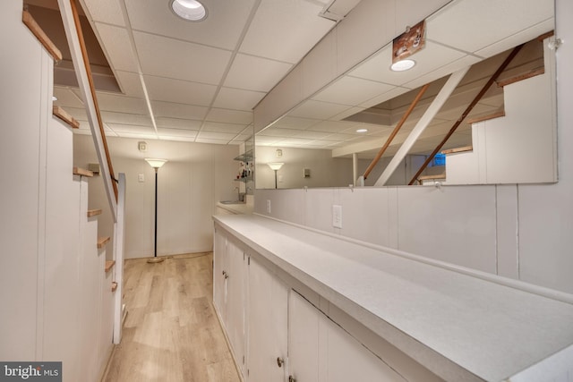 bar featuring a paneled ceiling, light hardwood / wood-style floors, and white cabinets