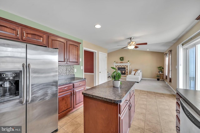 kitchen featuring lofted ceiling, tasteful backsplash, light tile patterned floors, stainless steel fridge, and a kitchen island