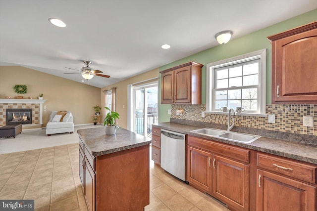 kitchen with a wealth of natural light, dishwasher, sink, decorative backsplash, and a center island