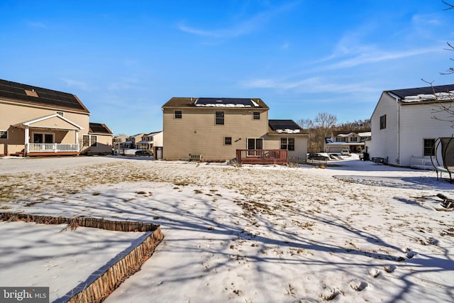 snow covered rear of property with a deck