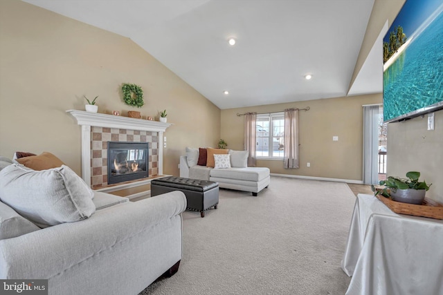 living room with a tiled fireplace, vaulted ceiling, and light colored carpet