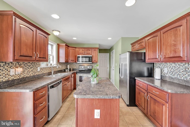 kitchen with sink, tasteful backsplash, light tile patterned floors, appliances with stainless steel finishes, and a kitchen island