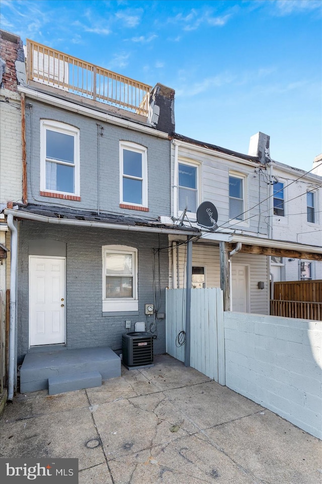 view of front of property featuring a balcony, a patio, and central air condition unit